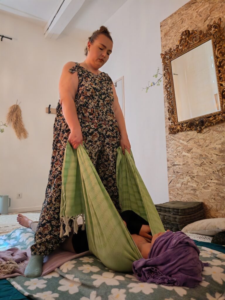 Femme recevant un soin Rebozo de renaissance avec bercements, serrage du corps et moment de profonde détente et recentrage