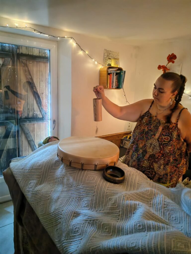 Praticienne utilisant un carillon pour harmoniser et réaligner les énergies pendant un soin rituel Rebozo pour femme dans le nord de la France